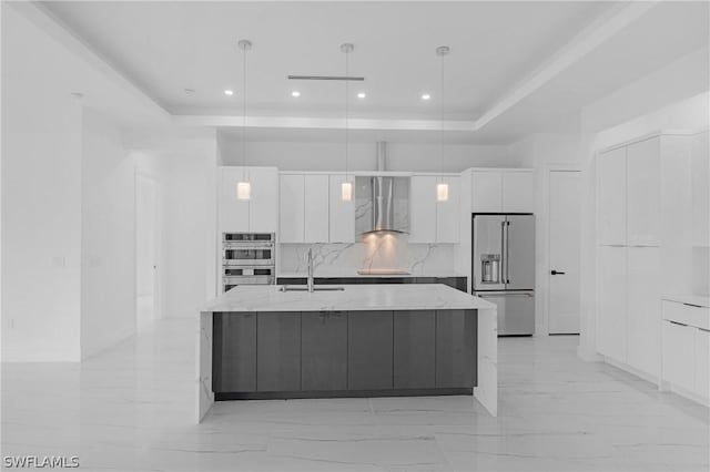 kitchen with white cabinetry, hanging light fixtures, appliances with stainless steel finishes, and wall chimney range hood