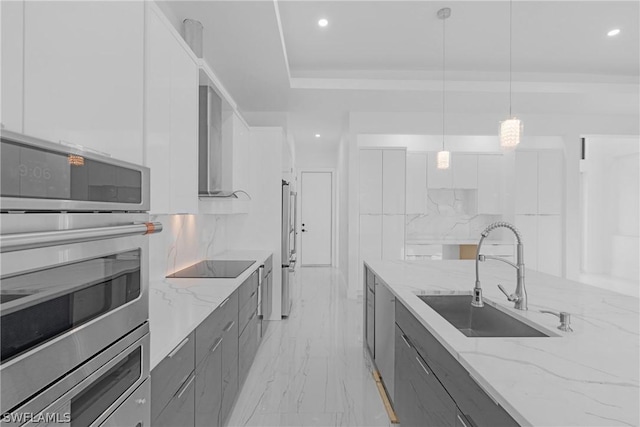 kitchen with light stone countertops, sink, hanging light fixtures, black electric stovetop, and white cabinets