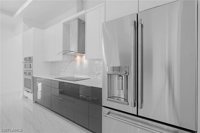 kitchen with decorative backsplash, white cabinetry, wall chimney exhaust hood, and appliances with stainless steel finishes