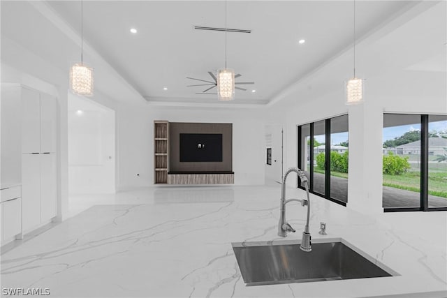 kitchen with ceiling fan, light stone countertops, sink, and hanging light fixtures