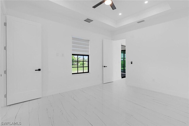 unfurnished room with ceiling fan and a raised ceiling