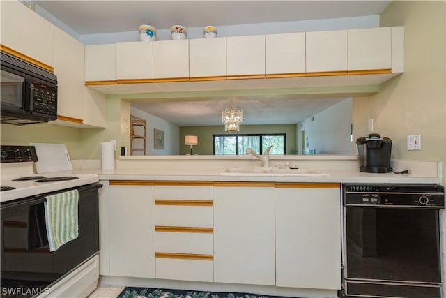 kitchen with kitchen peninsula, sink, white cabinets, a notable chandelier, and black appliances