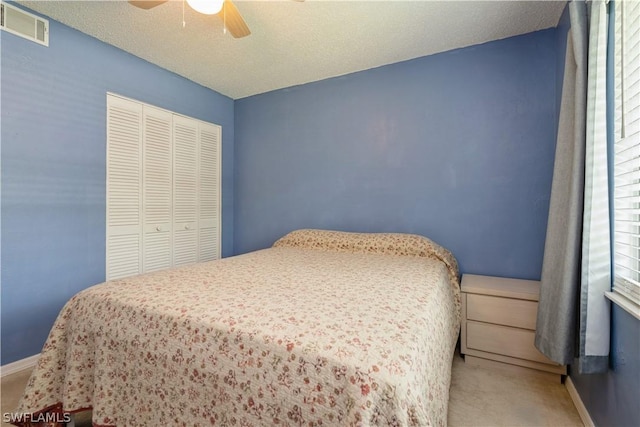 bedroom with ceiling fan, a textured ceiling, a closet, and carpet floors