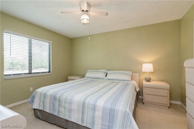 carpeted bedroom featuring ceiling fan and a textured ceiling