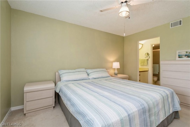 carpeted bedroom featuring a textured ceiling, connected bathroom, and ceiling fan