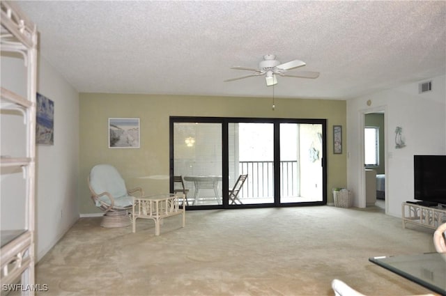 unfurnished living room featuring a textured ceiling, carpet, visible vents, and ceiling fan