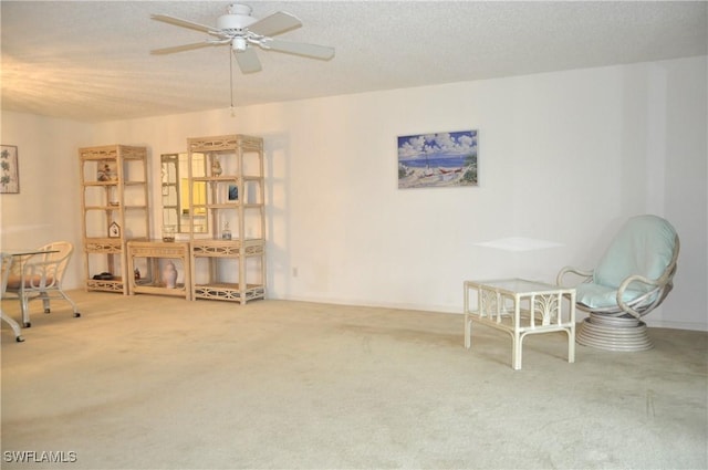 living area with a textured ceiling, a ceiling fan, and carpet floors