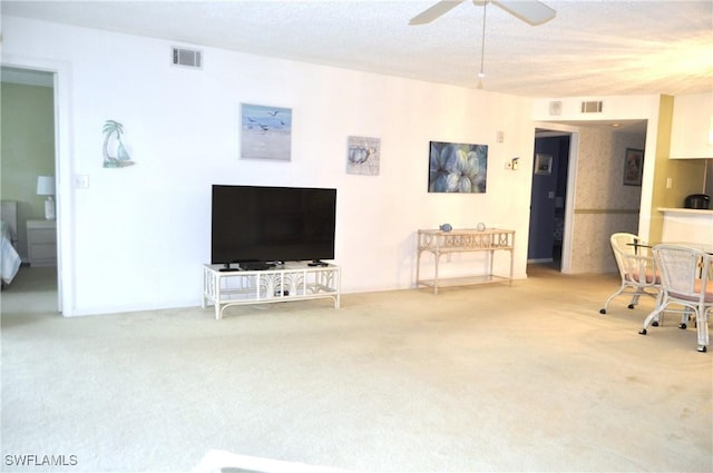 unfurnished living room featuring ceiling fan, a textured ceiling, and carpet flooring