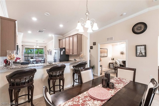 tiled dining space with a chandelier, lofted ceiling, and ornamental molding