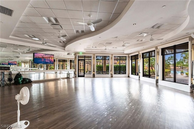 interior space with a paneled ceiling, hardwood / wood-style flooring, a raised ceiling, and ceiling fan