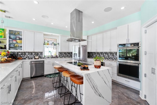 kitchen with white cabinetry, a kitchen island, island exhaust hood, and appliances with stainless steel finishes