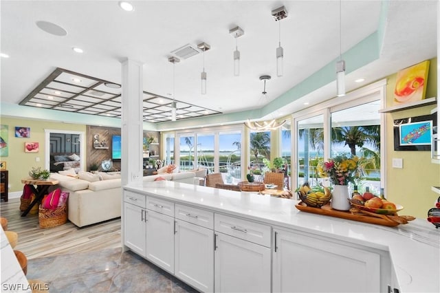 kitchen featuring light stone countertops, pendant lighting, and white cabinets