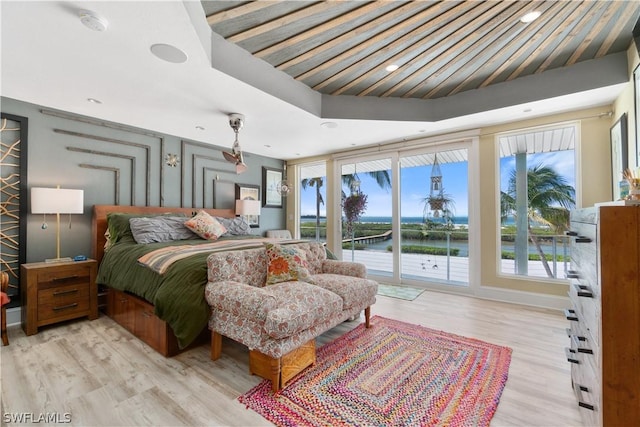 bedroom featuring a water view, access to exterior, and light wood-type flooring