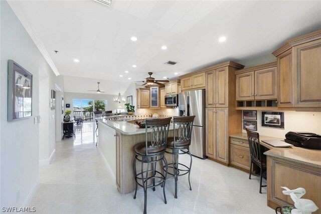 kitchen with ceiling fan, stainless steel appliances, a kitchen island, light tile patterned floors, and a kitchen breakfast bar