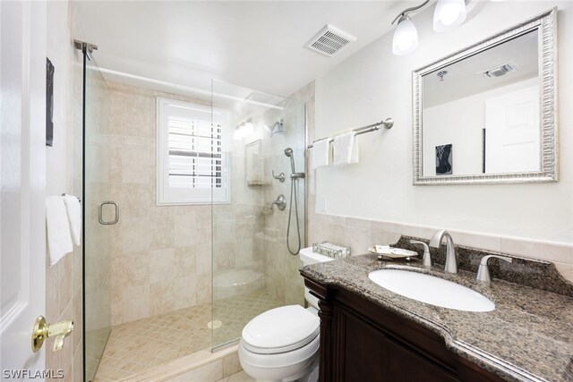 bathroom featuring tasteful backsplash, toilet, vanity, and an enclosed shower