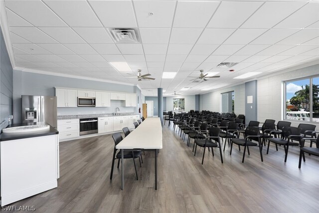 dining space with a drop ceiling, crown molding, hardwood / wood-style floors, and ceiling fan