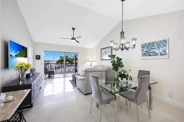 tiled dining space featuring ceiling fan with notable chandelier and high vaulted ceiling