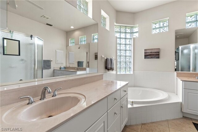 bathroom featuring tile flooring, a relaxing tiled bath, vanity, and ceiling fan