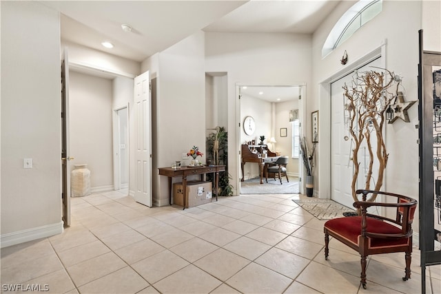 foyer entrance with a towering ceiling, a wealth of natural light, and light tile floors