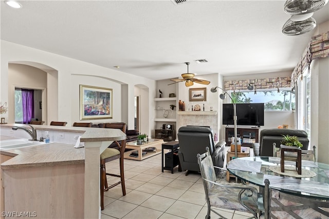 dining space with sink, built in shelves, ceiling fan, and light tile floors