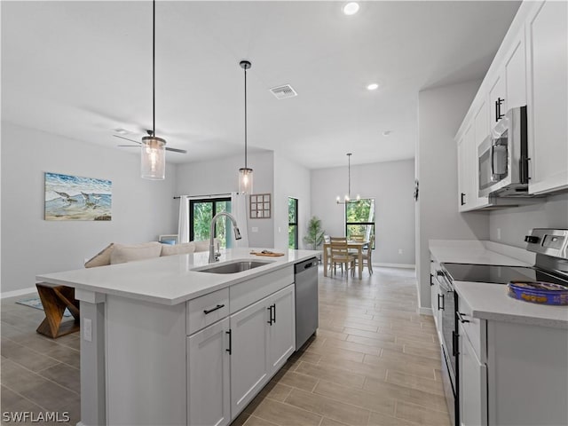 kitchen featuring a center island with sink, ceiling fan with notable chandelier, sink, white cabinetry, and stainless steel appliances