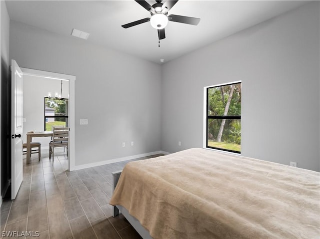 bedroom featuring hardwood / wood-style floors and ceiling fan with notable chandelier