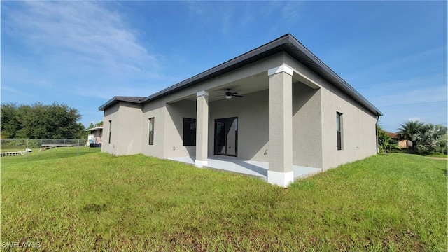 back of property with a patio, ceiling fan, and a lawn