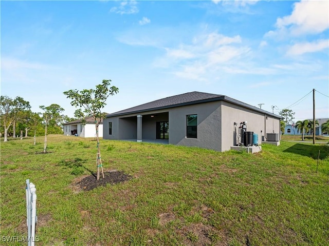 2917 NW 19th Ter, Cape Coral, FL 33993 - back of house featuring stucco siding, a yard, and central AC