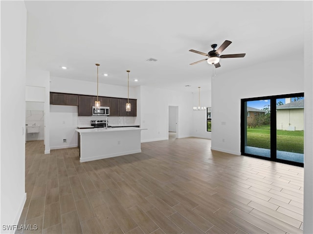 kitchen featuring stainless steel appliances, light hardwood / wood-style floors, dark brown cabinets, and a center island with sink