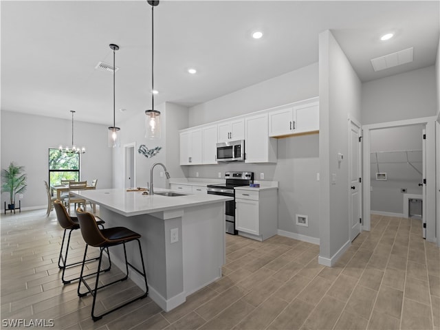 kitchen featuring pendant lighting, sink, an island with sink, appliances with stainless steel finishes, and white cabinetry