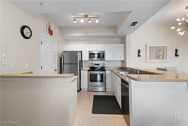 kitchen featuring an inviting chandelier, white cabinets, appliances with stainless steel finishes, light tile patterned flooring, and kitchen peninsula