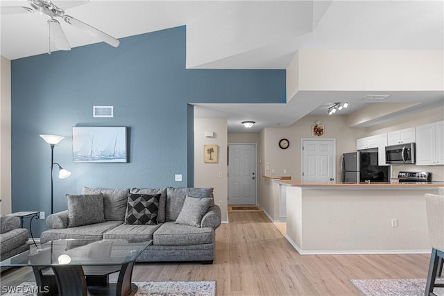 living room with ceiling fan, high vaulted ceiling, and light hardwood / wood-style floors