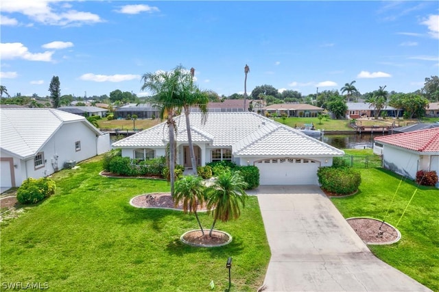 view of front of home featuring a front lawn, a water view, and a garage