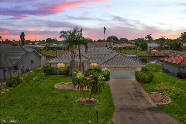 view of front of property featuring a garage, a yard, and a water view