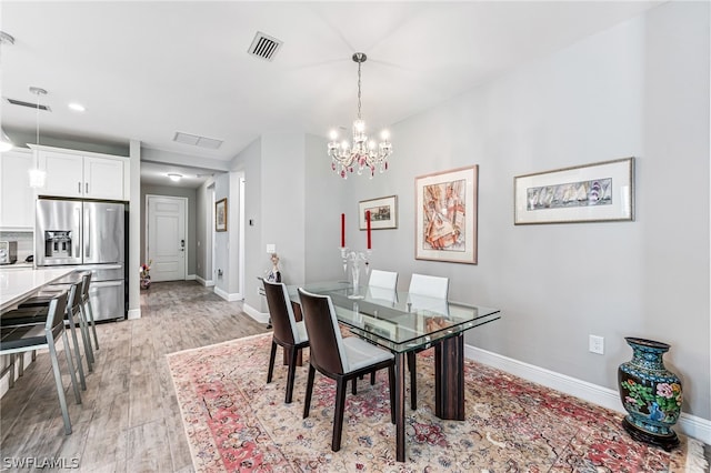 dining room with light wood-type flooring and a chandelier