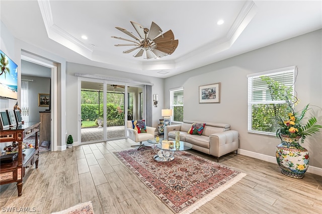 living room featuring a healthy amount of sunlight, a tray ceiling, and light hardwood / wood-style flooring