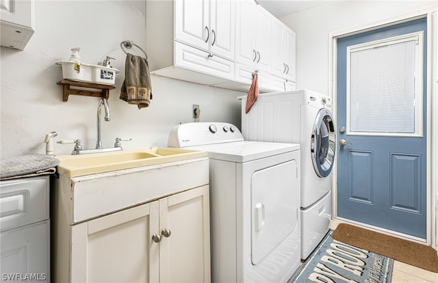 clothes washing area featuring tile patterned flooring, washer and dryer, and cabinets