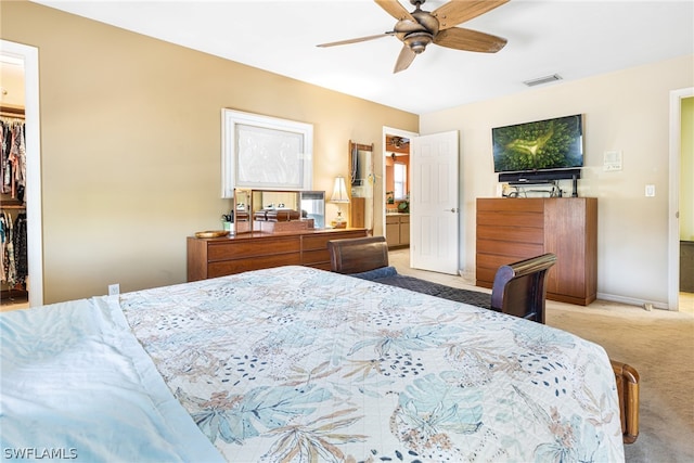 bedroom featuring ceiling fan, light carpet, a closet, and a walk in closet