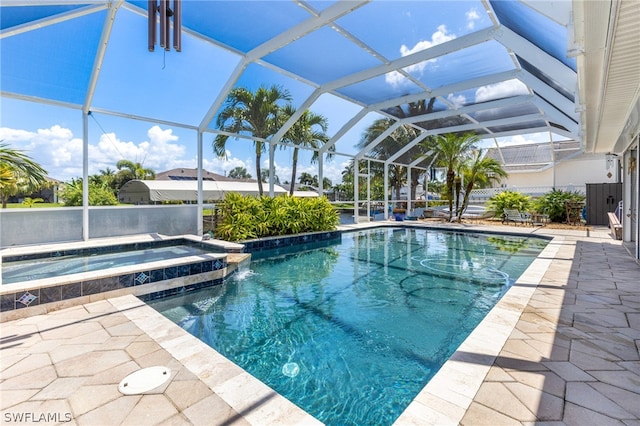 view of pool with a patio, glass enclosure, and an in ground hot tub