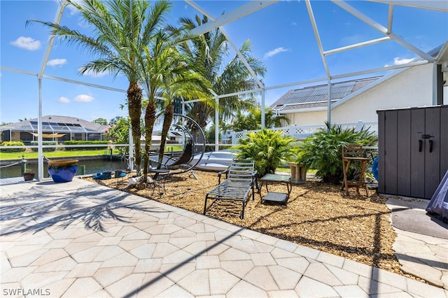 view of patio / terrace featuring a lanai and a water view