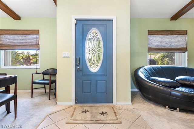 foyer with light carpet and beamed ceiling