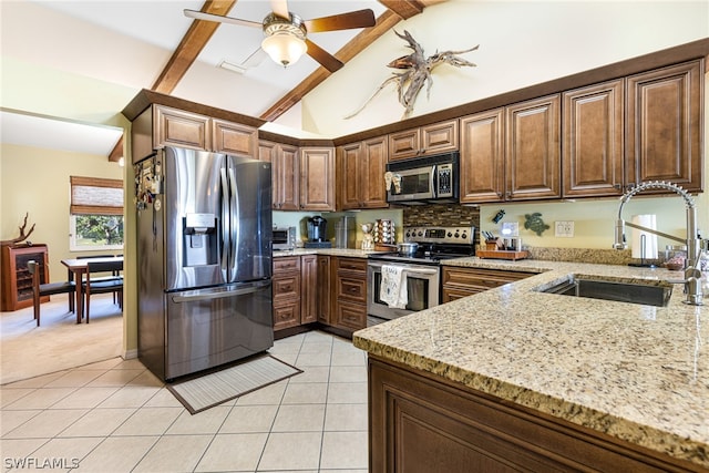 kitchen with appliances with stainless steel finishes, sink, light stone counters, and light tile patterned flooring