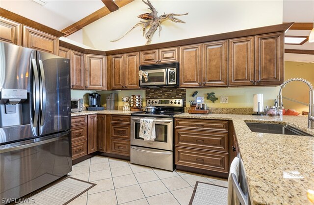 kitchen featuring light tile patterned floors, sink, appliances with stainless steel finishes, and light stone countertops