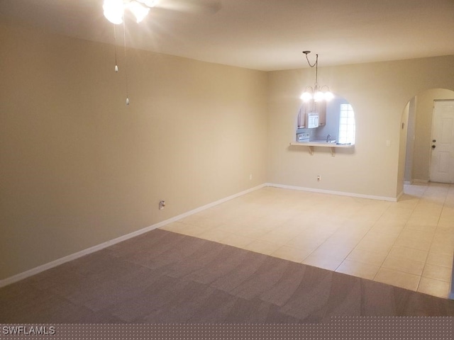 empty room featuring ceiling fan with notable chandelier and sink