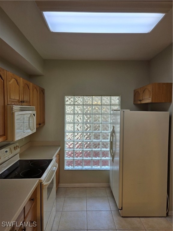 kitchen featuring light tile patterned flooring and white appliances