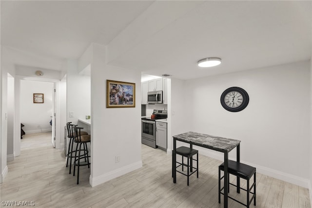 201 Santa Clara Dr Unit 13, Naples, FL 34104 - kitchen featuring light wood finished floors, a kitchen breakfast bar, stainless steel appliances, baseboards, and white cabinetry