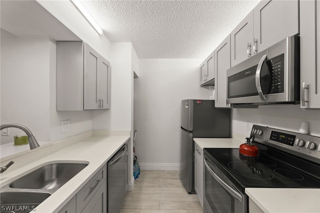 kitchen featuring gray cabinetry, stainless steel appliances, a textured ceiling, and sink