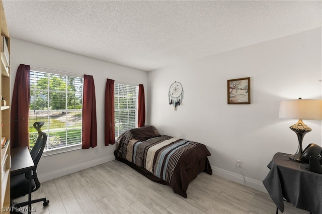 bedroom with light hardwood / wood-style flooring and a textured ceiling