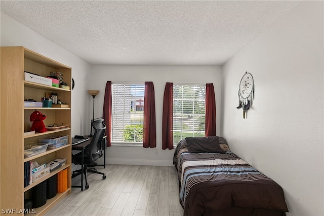 bedroom with a textured ceiling and light wood-type flooring