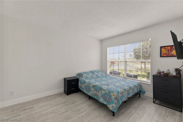 bedroom featuring light hardwood / wood-style flooring and a textured ceiling